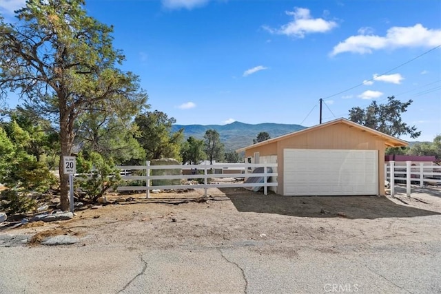 exterior space with a garage, an outbuilding, fence, and a mountain view