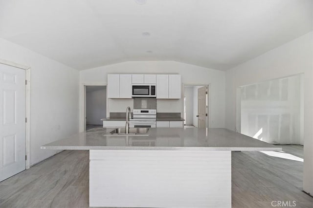 kitchen featuring a center island with sink, white cabinets, lofted ceiling, white electric range, and a sink