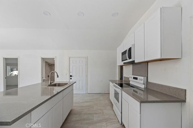 kitchen with a sink, a center island with sink, white cabinetry, and electric stove