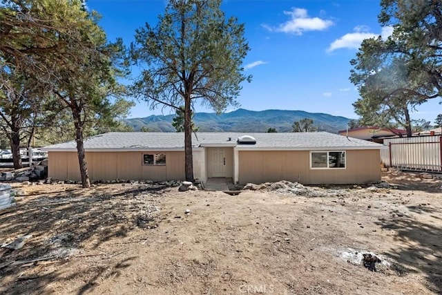 rear view of house featuring a mountain view and fence