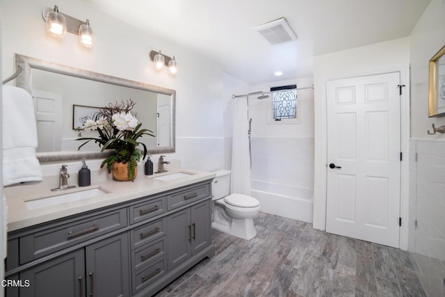 full bathroom with shower / bath combo with shower curtain, tile walls, vanity, toilet, and hardwood / wood-style flooring