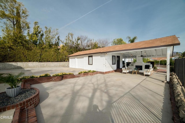 rear view of property featuring a patio, an outdoor fireplace, and ceiling fan