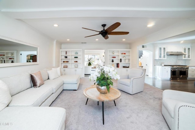 living room featuring light hardwood / wood-style floors, crown molding, built in shelves, and ceiling fan