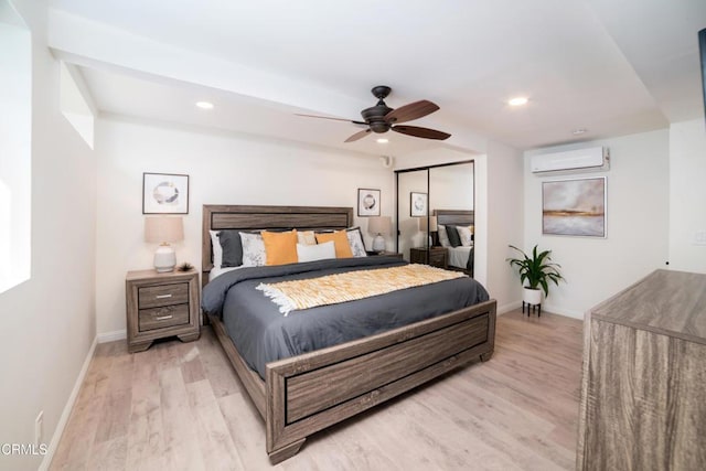 bedroom featuring an AC wall unit, light hardwood / wood-style floors, a closet, and ceiling fan