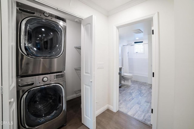 laundry area with stacked washing maching and dryer, ornamental molding, and dark hardwood / wood-style floors