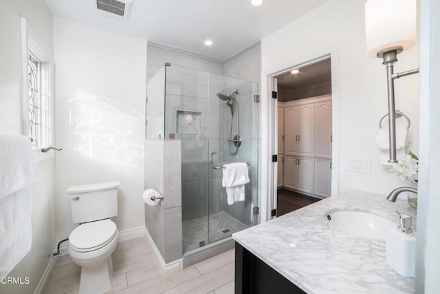 bathroom featuring vanity, toilet, and a shower with shower door