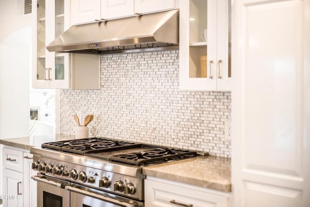 kitchen with white cabinetry, light stone counters, tasteful backsplash, and range with two ovens