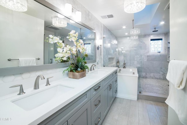 bathroom with an inviting chandelier, separate shower and tub, and vanity