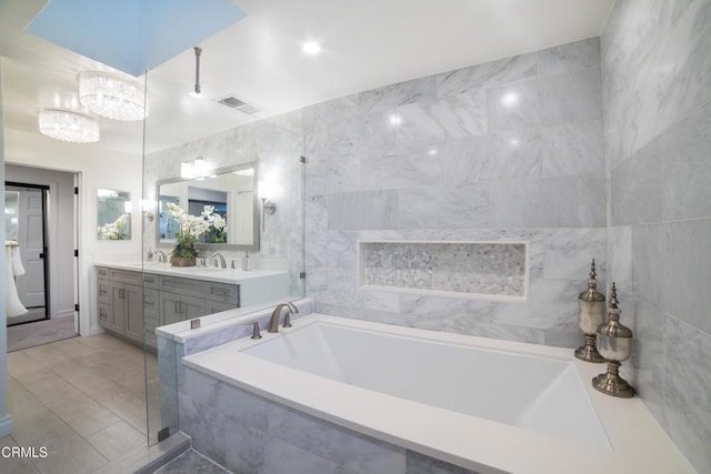 bathroom with tiled bath, tile walls, and vanity