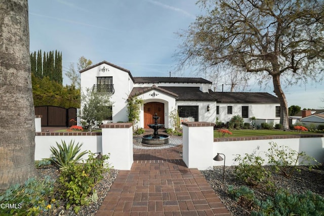 mediterranean / spanish-style house with a tiled roof, fence, and stucco siding