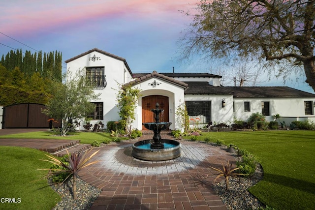 mediterranean / spanish house featuring a yard, a gate, and stucco siding