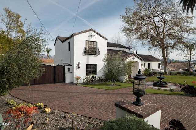 rear view of property with a tile roof, a gate, and stucco siding