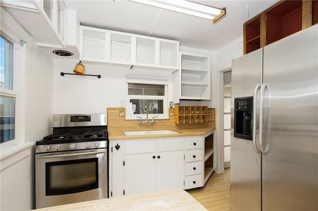 kitchen featuring open shelves, stainless steel appliances, tasteful backsplash, light wood-style flooring, and white cabinetry