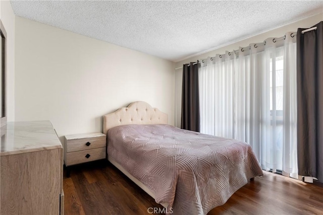 bedroom with a textured ceiling and dark hardwood / wood-style flooring