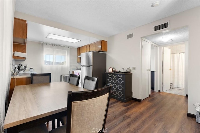 dining area with a textured ceiling and dark hardwood / wood-style flooring