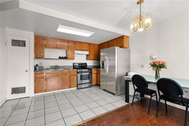 kitchen with an inviting chandelier, appliances with stainless steel finishes, sink, light tile patterned floors, and pendant lighting