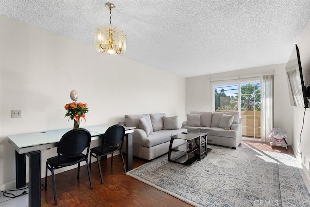 living room featuring a textured ceiling, dark hardwood / wood-style floors, and a notable chandelier