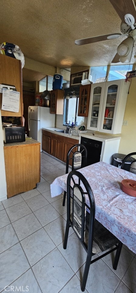 kitchen featuring sink, dishwasher, a textured ceiling, and light tile patterned flooring