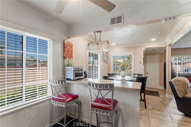 dining room featuring visible vents, crown molding, light tile patterned floors, baseboards, and ceiling fan