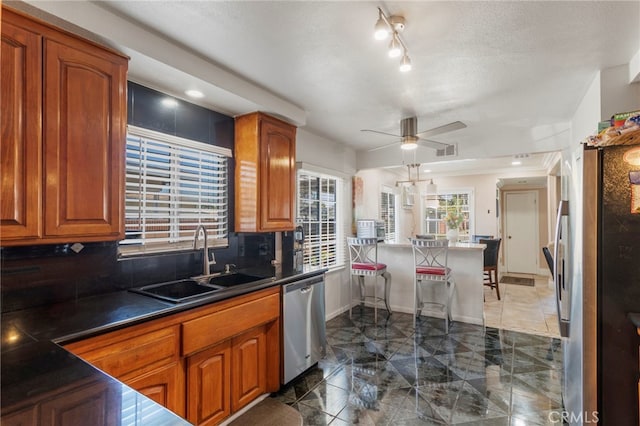 kitchen with sink, ceiling fan, stainless steel appliances, a textured ceiling, and kitchen peninsula