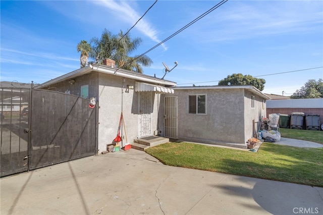 back of property with stucco siding, a gate, a patio, fence, and a yard