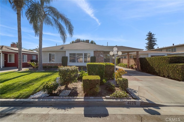 view of front of property with driveway, brick siding, and a front yard