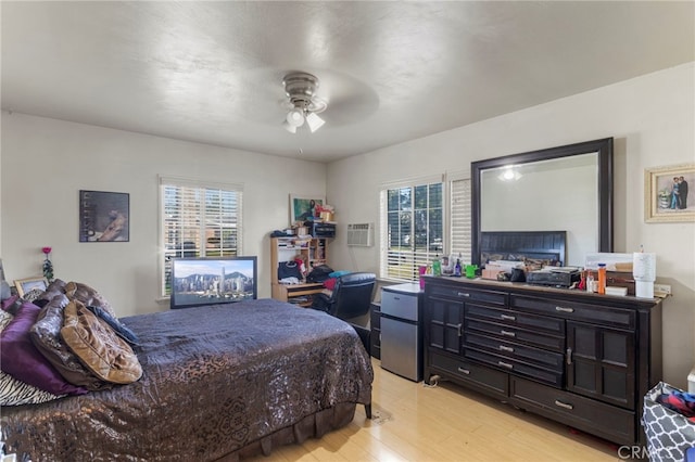 bedroom featuring light wood-type flooring, multiple windows, refrigerator, and a ceiling fan