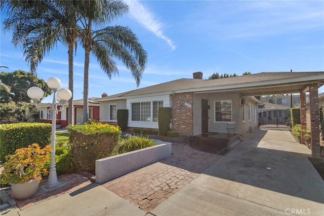 single story home with a gate, brick siding, and stucco siding