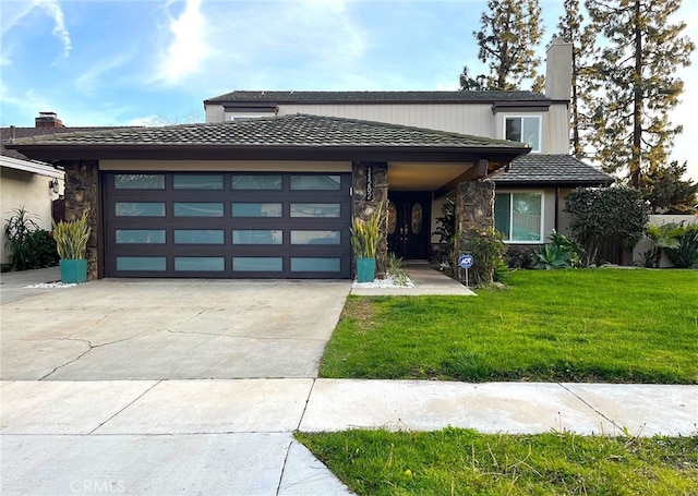 view of front facade with concrete driveway, a front yard, a chimney, stone siding, and an attached garage