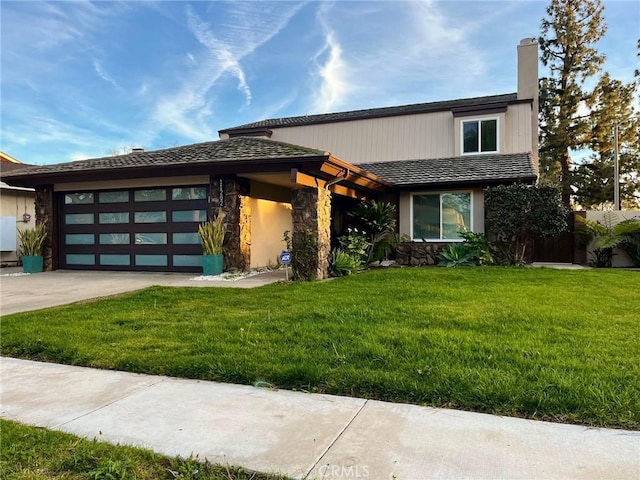 view of front of property with a garage, a chimney, concrete driveway, and a front lawn