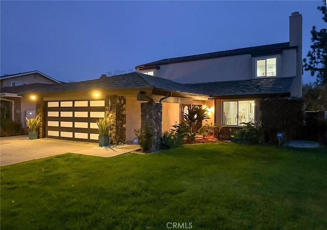 view of front of property with an attached garage, a chimney, driveway, and a yard