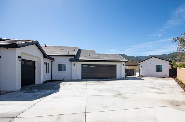 view of front of house featuring a mountain view, a tiled roof, a garage, concrete driveway, and stucco siding