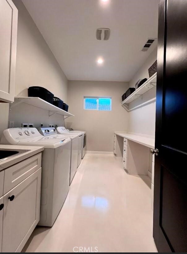 washroom with visible vents, washing machine and clothes dryer, and cabinet space