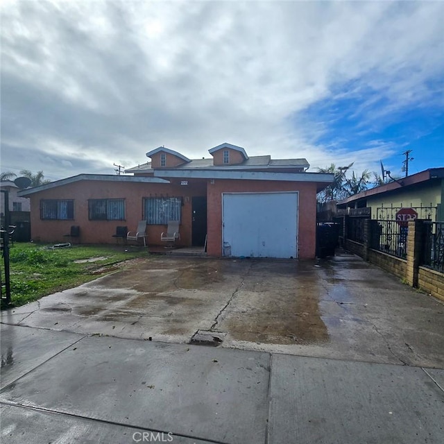 ranch-style home featuring stucco siding, an attached garage, concrete driveway, and fence