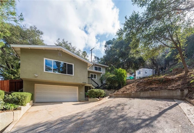 view of front of home featuring a garage, fence, concrete driveway, and stucco siding