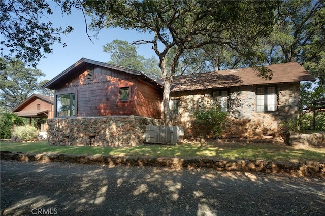 view of home's exterior featuring stone siding and a lawn