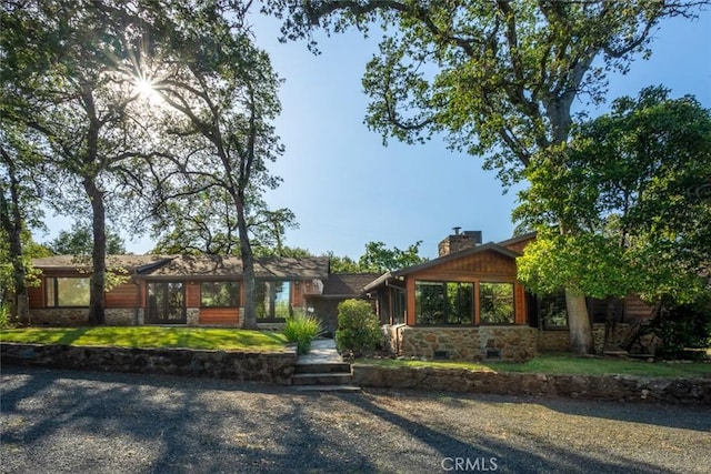 view of front of property with stone siding, a chimney, and a front yard