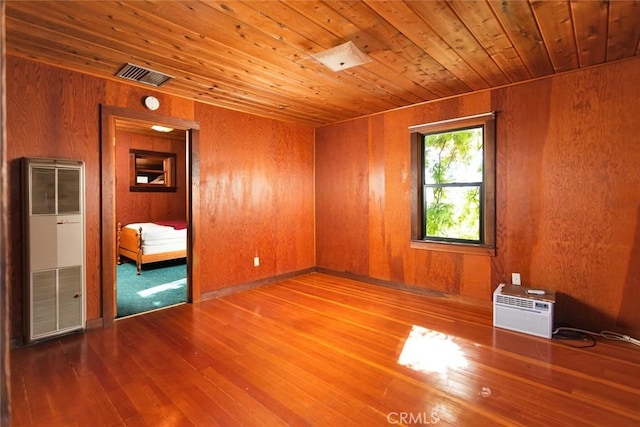 spare room featuring wood walls, wood ceiling, visible vents, and wood finished floors