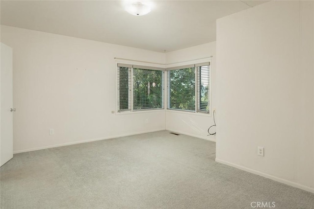 unfurnished room featuring visible vents, baseboards, and light colored carpet