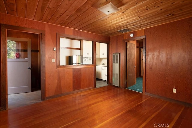 interior space with wooden ceiling, wooden walls, a sink, wood finished floors, and visible vents