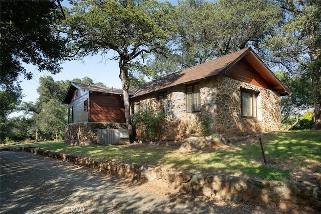 view of property exterior with stone siding and a lawn