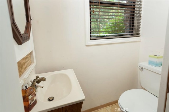 half bath featuring a sink, toilet, and baseboards