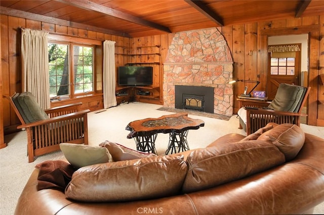 carpeted living room featuring wooden ceiling, wood walls, a stone fireplace, and beamed ceiling