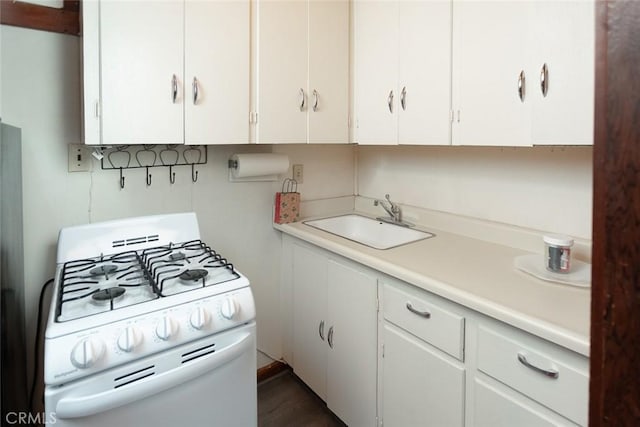 kitchen featuring light countertops, white cabinetry, a sink, and white gas range oven