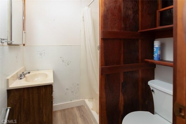 bathroom featuring tile walls, toilet, a shower stall, vanity, and wood finished floors