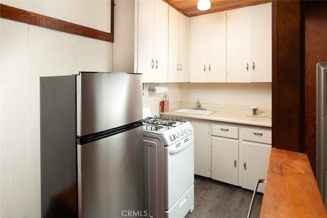 kitchen featuring a sink, white cabinetry, light countertops, white gas range oven, and freestanding refrigerator