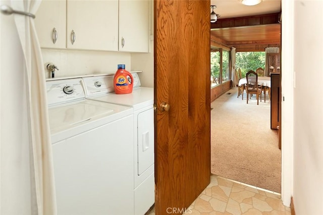 washroom with washing machine and dryer, light carpet, and cabinet space