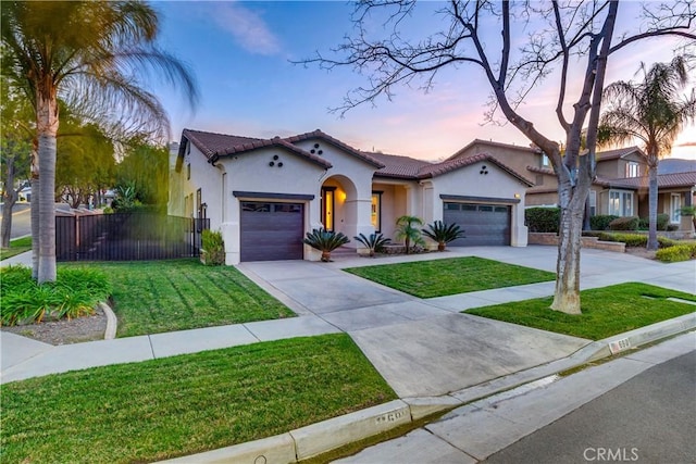 mediterranean / spanish-style house featuring a front lawn, concrete driveway, an attached garage, and stucco siding