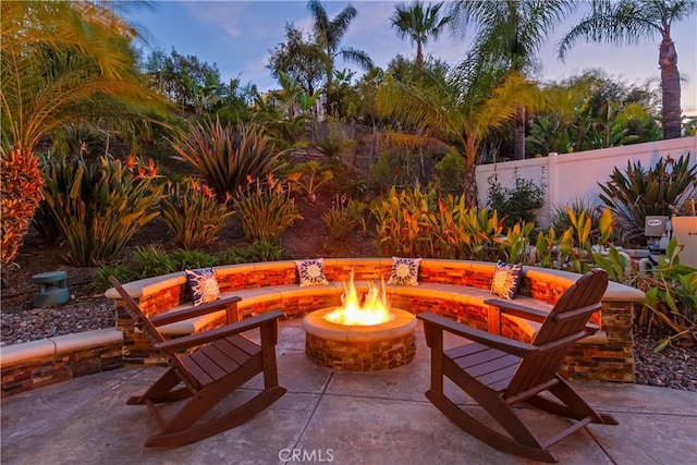 patio terrace at dusk featuring fence and a fire pit