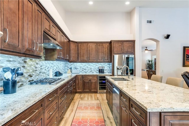 kitchen with wine cooler, arched walkways, visible vents, appliances with stainless steel finishes, and under cabinet range hood